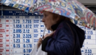 A woman holds an umbrella to protect herself from the rain, as she a walks in front of a currency exchange office in Sofia on May 30, 2025. (Photo by Nikolay Doychinov / AFP)

