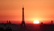 The sun rises by the Eiffel Tower and the Sacre Coeur Basilica ontop of the Montmartre hill in Paris on July 1, 2025, as the city is on red alert for high temperatures, with the top of the Eiffel Tower shut, polluting traffic banned and speed restrictions in place as a searing heatwave gripped Europe. Photo by Thibaud MORITZ / AFP