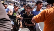 Children queue with pots to receive meals from a charity kitchen in Gaza City on July 14, 2025. Photo by BASHAR TALEB / AFP.
