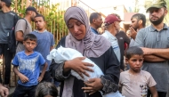 The mother of Yahya Fadi al-Najjar, an infant who died due to malnourishment, mourns as she holds his body during the funeral at Nasser Medical Complex in Khan Yunis in the southern Gaza Strip on July 20, 2025. (Photo by AFP)