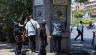 Iranians drink water from a public street fountain amid soaring temperatures in Tehran on July 22, 2025. (Photo by AFP)
