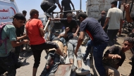 People transport men, wounded as he waited for humanitarian aid, along al-Rashid street in western Jabalia on June 22, 2025, after trucks carrying humanitarian aid entered the northern Gaza Strip through the Israeli-controlled Zikim border crossing. (Photo by Omar AL-QATTAA / AFP)
