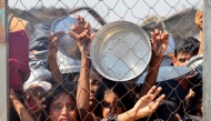 Palestinians, mostly children, push to receive a hot meal at a charity kitchen in the Mawasi area of Khan Yunis in the southern Gaza Strip on July 22, 2025. (Photo by AFP)
