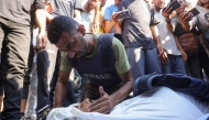 A colleague mourns Palestinian journalist Adam Abu Harbid, killed in overnight Israeli strikes, during his funeral at the Al-Shifa hospital in Gaza City on July 25, 2025. Photo by BASHAR TALEB / AFP.