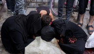 Women and a boy mourn by the body of a victim killed by gunfire while waiting for aid trucks entering the northern Gaza Strip through the Zikim crossing, as it lays on the ground at the Shifa Hospital in Gaza City on July 27, 2025. (Photo by Omar AL-QATTAA / AFP)
