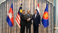 Malaysia's Prime Minister Anwar Ibrahim (C), Cambodia's Prime Minister Hun Manet (L) and Thailand's acting Prime Minister Phumtham Wechayachai (R) pose for photos as they shake hands following a press conference after talks on a possible ceasefire between Thailand and Cambodia in Putrajaya on July 28, 2025. (Photo by MOHD RASFAN / POOL / AFP)
