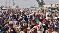 Palestinians carry humanitarian aid they received at the Rafah corridor as they walk in the Mawasi area of Rafah in the southern Gaza Strip yesterday. (AFP)