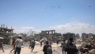 Palestinians in Jabalia in the northern Gaza Strip rush towards a plane conducting an airdrop of aid above the Palestinian territory on August 1, 2025. Photo by Bashar TALEB / AFP