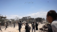 Palestinians in Jabalia in the northern Gaza Strip rush towards a plane conducting an airdrop of aid above the Israel-besieged Palestinian territory on August 1, 2025.  (Photo by Bashar Taleb / AFP)