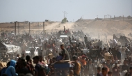Palestinians leave a food distribution point run by the US and Israeli-backed Gaza Humanitarian Foundation (GHF) group with bags and wooden pallets, near the Netsarim corridor in the central Gaza Strip yesterday. (AFP)