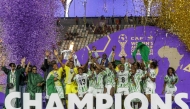 (Files) Nigeria's players celebrate with the trophy on the podium after winning the 2025 Women's Africa Cup of Nations final football match on July 26, 2025. (Photo by Abdel Majid Bziouat / AFP)