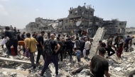 Palestinians hustle around a humanitarian parcel dropped by a military aircraft in Jabalia in the northern Gaza Strip on August 9, 2025. Photo by Bashar TALEB / AFP