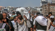 Displaced Palestinians carry food parcels as they raid trucks carrying humanitarian aid in Khan Yunis, in the southern Gaza Strip on August 9, 2025. Photo by AFP