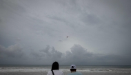 A helicopter flies over as a couple looks at La Pared beach as Category 5 Hurricane Erin approaches in Luquillo, Puerto Rico on August 16, 2025. (Photo by Ricardo Arduengo / AFP)