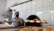 An Egyptian baker works in front of an oven at a bakery in Riyadh on August 14, 2025, during the soaring summer heat. (Photo by Fayez Nureldine / AFP)
