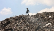 A Palestinian girl searches for things to rescue at a garbage waste dump in Gaza City on August 18, 2025. (Photo by Omar Al-Qattaa / AFP)