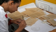 This photograph taken on June 20, 2025 shows an employee working to preserve an old book inside the paper conservation lab of the conservation department at the Indira Gandhi National Centre for Arts (IGNCA), in New Delhi. (Photo by Money Sharma / AFP)