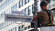 A worker installs a street sign bearing what is supposed to become the new name for the 'Mohrenstrasse' (Moor street), the 'Anton-Wilhelm-Amo-strasse' in Berlin on August 22, 2025. (Photo by John MacDougall / AFP)
