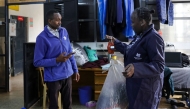 A resident uses digital credit earned from delivering plastic waste to a Human Needs Project (HNP) collection point to pay for laundromat services in the Kibera informal settlement of Nairobi. (Photo by Tony Karumba / AFP)