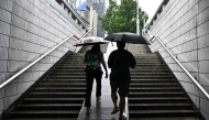 People use umbrellas to protect themselves from the rain in Beijing on August 27, 2025. (Photo by Pedro PARDO / AFP)