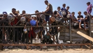 Children gather by a fence as they try to get rice from a charity kitchen providing food for free in the west of Gaza City, on August 28, 2025. Photo by BASHAR TALEB / AFP