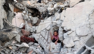 A boy climbs from out of the rubble of a collapsed building that was hit by bombardment in the Nuseirat camp for Palestinian refugees in the central Gaza Strip on August 30, 2025.  (Photo by Eyad Baba / AFP)