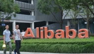 This file photo taken on May 27, 2022 shows staff members walking past the logo of Chinese e-commerce giant Alibaba at its headquarters in Hangzhou, in China's eastern Zhejiang province. Photo by AFP

