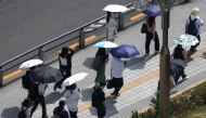 People with umbrellas walk in the scorching sun in Tokyo on September 1, 2025. (Photo by Kazuhiro NOGI / AFP)