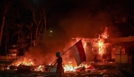 A protester walks with an Indonesian flag in front of a police headquarters that was set on fire and looted during demonstrations in Surabaya on August 31, 2025. Photo by Juni KRISWANTO / AFP