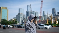 A woman wearing sun protective clothing crosses a street in Beijing on June 23, 2025. Photo by WANG Zhao / AFP