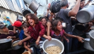 Palestinians shove to receive a hot meal from a charity kitchen in the Nuseirat refugee camp in the Israel-besieged Gaza Strip on September 4, 2025, where the UN has declared famine after nearly two years of war. (Photo by Eyad BABA / AFP)
