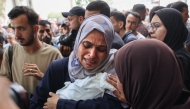 Graphic content / A Palestinian woman cries as she carries the body of a baby killed in Israeli strikes on Gaza City at dawn, before a funeral procession outside the Al-Shifa hospital on September 4, 2025. (Photo by Omar AL-Qattaa / AFP)