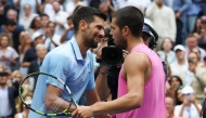 Spain's Carlos Alcaraz and Serbia's Novak Djokovic (L) hug at the net after Alcaraz's victory on September 5, 2025. (Photo by Timothy A. Clary / AFP)
 