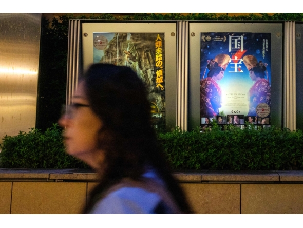 A woman walks past the poster of Japanese movie 