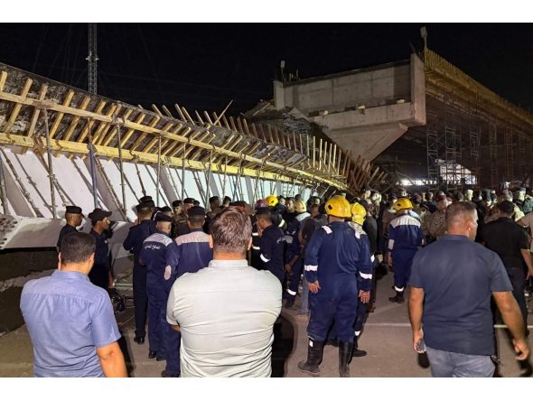 First responders and onlookers gather in front of a bridge under construction, after a section of it collapsed, killing two people and injuring others, in Karbala in southern Iraq late on September 6, 2025. Photo by Salman AMIN / AFP