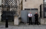 Security guards stand beside a metal barrier covering up an artwork by street artist Banksy, depicting a judge using a gavel to beat a protester using a placard as protection, on an exterior wall of the Royal Courts of Justice in London, on September 8, 2025. (Photo by Carlos Jasso / AFP)
