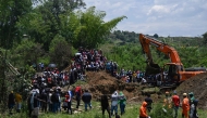 People look at an excavator working at the site where an illegal gold mine collapsed with seven miners trapped in Santander de Quilichao, department of Cauca, Colombia, on September 12, 2025. (Photo by Joaquin SARMIENTO / AFP)

