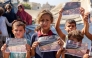 Children hold some of the leaflets dropped by the Israeli military, urging evacuation to al-Mawasi in the southern Gaza Strip, as occupation forces step attacks, on September 12, 2025. (Photo by Omar Al-Qattaa / AFP)
