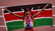 First placed Kenya's athlete Beatrice Chebet celebrates with her country's flag at the end of the women's 10000m final during the World Athletics Championships in Tokyo on September 13, 2025. (Photo by Yuichi Yamazaki / AFP)