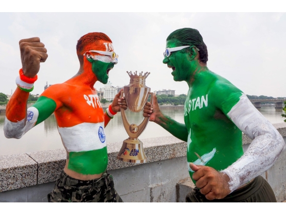Fans with their bodies painted in national flags of India (L) and Pakistan pose in Ahmedabad on September 13, 2025, with a replica of the Asia Cup 2025 trophy on the eve of the Twenty20 international cricket match between India and Pakistan in Dubai. (Photo by Sam PANTHAKY / AFP)
