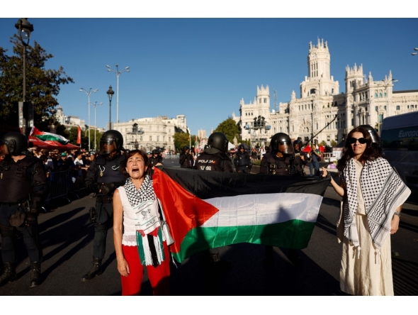 Two women hold a Palestinian flag after Pro-Palestinian protesters invaded the street during the 21st and last stage of the Vuelta a Espana 2025, a 101 km race near Cibeles fountain in Madrid on September 14, 2025.  (Photo by Oscar Del Pozo / AFP)
