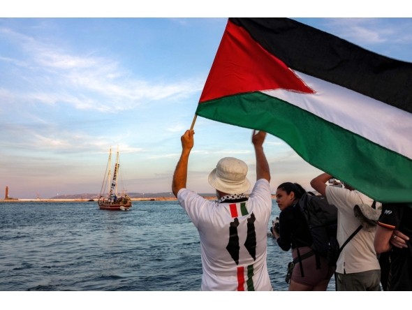 A man waves a Palestinian flags to other activists and human rights defenders riding aboard a vessel departing from Tunisia's northern port of Bizerte on September 14, 2025 to join the last boats taking part in the Global Sumud Flotilla. (Photo by Mohamed Fliss / AFP)