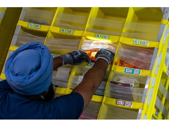 A worker grabs products from a bin at Amazon Fulfillment Center SCK6 in Tracy, California. Photo credit: Jungho Kim/For The Washington Post
