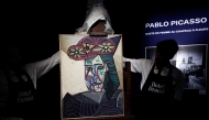 Employees unveal a painting by French artist Pablo Picasso titled 