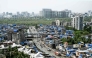 This photograph taken on July 12, 2025 shows high-rise buildings around the cramped shanties of Dharavi, a slum settlement in Mumbai. (Photo by Indranil Mukherjee / AFP)