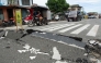 Vehicles maneuver past a damaged part of a road in Bogo City on October 1, 2025, after a powerful 6.9 magnitude earthquake jolted the central Philippines. (Photo by Ted Aljibe / AFP)