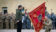 This handout photograph taken and released by the Ukrainian Presidential Press Service on October 1, 2025, shows Ukraine's President Volodymyr Zelensky holding a flag insignia as a serviceman pays his respect during a ceremony marking Defenders' Day, a holiday honoring veterans and fallen members of the Ukrainian armed forces. (Photo by Handout  / AFP)