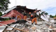 Rescuers search for three people who were reported missing under the rubble of a collapsed building in Bogo City on October 1, 2025. (Photo by Ted Aljibe / AFP)