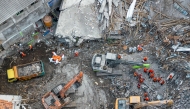An aerial view shows rescuers searching for victims at the Al Khoziny Islamic boarding school in Sidoarjo, East Java, on October 5, 2025, after a multi-story building at the school collapsed during prayers. (Photo by Dicky Bisinglasi / AFP)