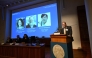 Nobel Committee Secretary General Thomas Perlmann (R) addresses journalists in front of a screen displaying the portraits of (L-R) Mary E Brunkow, Fred Ramsdell and Shimon Sakaguchi during a press conference. (Photo by Jonathan Nackstrand / AFP)